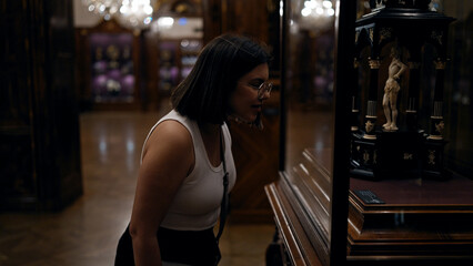 Young beautiful hispanic woman looking at art exhibition at imperial treasure museum in Vienna