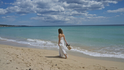 A young, beautiful hispanic woman strolls along the serene beach in pescoluse, salento, puglia, italy, enjoying the gentle waves and picturesque landscape.