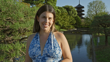 Beautiful hispanic woman standing, smiling confidently in front of japan's to-ji temple, radiating...
