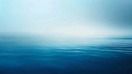 A serene seascape with a calm blue ocean and a misty horizon. The image evokes a sense of tranquility and peace.