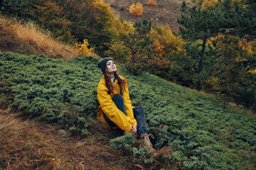 Woman relaxing on grassy hill in the vibrant colors of autumn forest during a peaceful retreat trip