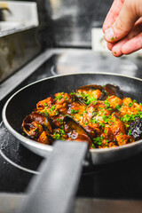 Close-up of a hand holding a sizzling frying pan with seafood