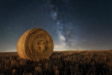 Mown cereal field in Palencia with straw rollers and in the background the Milky Way in a sky full...