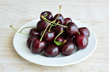 cherries with stems on the white plate close up 