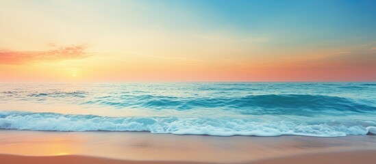 Obraz premium Golden sand beach with clear blue ocean and a sunset in the background, ideal for a summer or spring abstract background with copy space image.