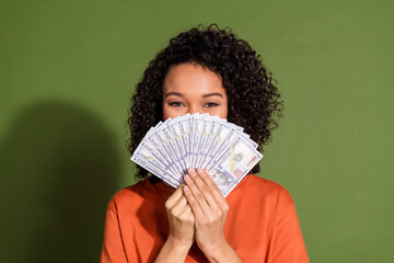 Photo portrait of lovely young lady cover face money dressed stylish orange garment isolated on...