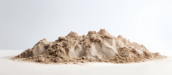 Dry beach sand piled up with a white backdrop for a copy space image.