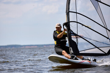 Naklejka premium Young man surfing the wind in splashes of water