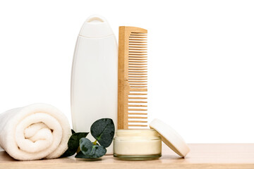 Set for spa treatments. White shampoo and white towel. Wooden comb.