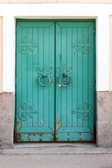 Ancient green wooden door in urban stone wall