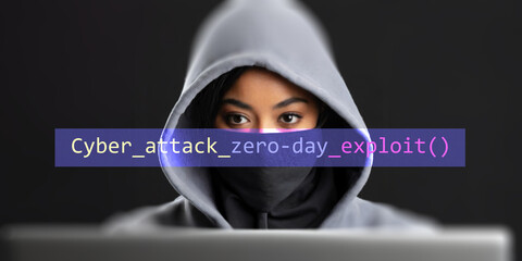 Zero-day attack text in foreground screen, anonymous hacker hidden with hoodie in the blurred background. Vulnerability text in binary system code on editor program.