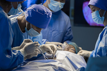 Surgeons team working with Monitoring of patient in surgical operating room. The doctors and nurses brainstorm power assisted surgery. A team of professional doctors perform surgery in a hospital