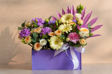 Bouquet of assorted flowers rests gracefully in a luxurious purple box, showcasing a blend of colors and textures.