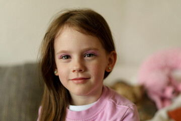 smiling cute little girl with painted eyes in the middle of the room