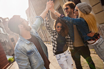 Group of friends high-fiving in the street during daytime