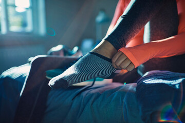 Close up of a woman in sportswear putting on socks at home