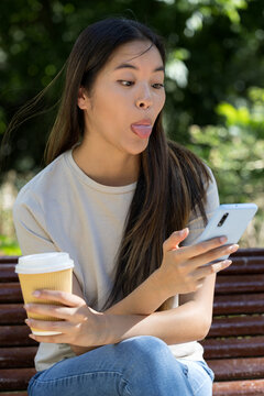 Teenage girl holds her phone while teasingly sticking out her tongue