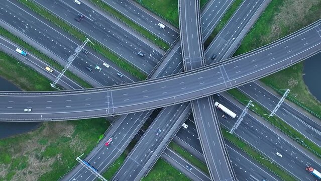 Aerial drone view of a multi-level highway intersection with moving cars near the city of Rotterdam, The Netherlands. Trucks move along a multi-level road junction. The concept of the urban.