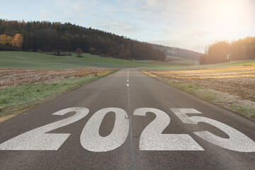 The word 2025 written on highway road in the middle of empty asphalt road at golden sunset and beautiful blue sky. Concept for year 2025.