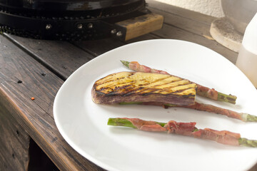 Preparing the table with various grilled dishes. A man cuts sausages and grilled vegetables.