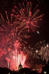 A dramatic shot of fireworks lighting up the night sky over a historic monument, capturing the essence of the celebration with plenty of dark sky for text.