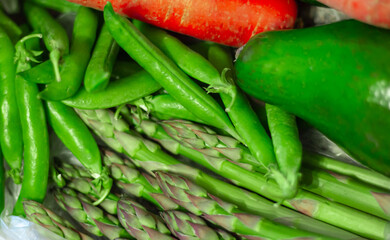 Ripe whole green avocados close up. Carrots, asparagus officinalis, green peas, green lettuce leaves.