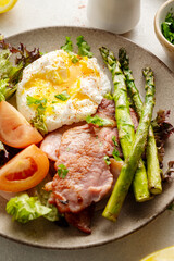 Healthy breakfast - asparagus wrapped with bacon, benedict poached egg and salad. 