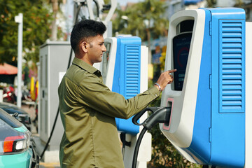 Electric car owner charging vehicle at public station