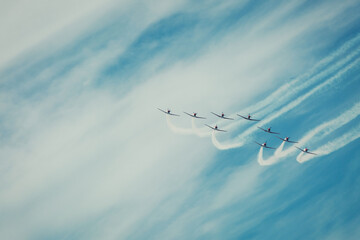 A group of airplanes make a formation with smoke trails