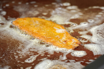 Fried schnitzel on the stove in the kitchen of a restaurant before serving the dish.