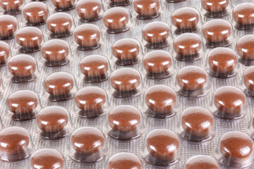 Background image: Brown tablets in blister packs. Medicines for treatment.