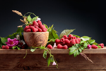 Summer still life with raspberries, meadow grasses and flowers on an old wooden table.