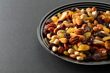 Mix of dried nuts and raisins on a black background.