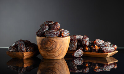Dates in wooden dish on a black background.