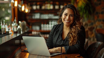 Happy young Latina businesswoman in suit working with laptop in a cafe or bar smiling confidently, for business owner, self employment, work from home, manager, small business, remote working concept.