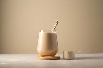 Protein powder and chocolate drink in a glass with straw, copy space.