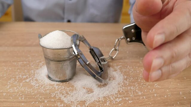 The man is handcuffed to a metal bucket with salt. Abuse of salt. Slow motion