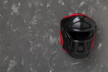 Black leather boxing helmet on concrete background, top view.