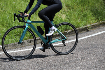 Fototapeta premium legs of Cliclist in tight cycling shorts and black leggings pedaling on a road bike during a road race