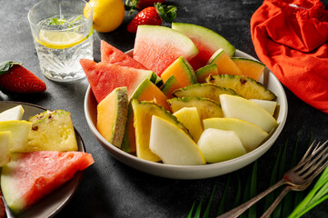 Fruits assortment platter antipasti, watermelon, pineapple, melon and strawberries. Dark background