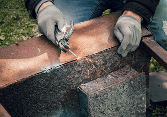 Close-up of the gloved hands of a master welder working on the restoration of an old metal structure in a workshop