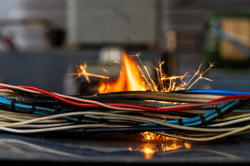 Flames, sparks, smoke between electrical cables, closeup. Short circuit in the twisted wires from...