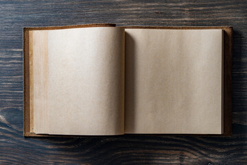 Opened empty vintage book in leather cover on wooden background, space for text, closeup, top view, copy space
