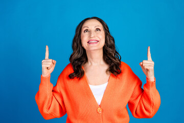 Photo portrait of gorgeous senior woman point up look empty space wear trendy orange outfit hairdo...