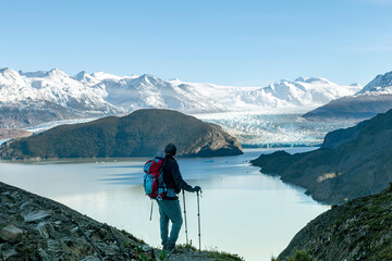 High angle view of man overlooking Glacier Grey and Lago Grey surrounded by snow covered mountains...