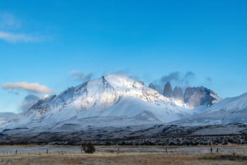 Torres del Paine National Park, Patagonia, Chile; Panoramic view of sun shining on snow covered Paine Massif mountains with three iconic granite towers (torres) during dawn along the W-trek route