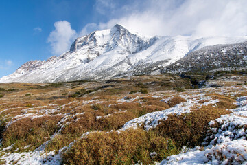 Torres del Paine National Park, Patagonia, Chile, Central sector W-trek snow covered hiking route with snow covered mountains of the Paine Massif against a white clouded blue sky