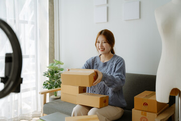 Startup small business entrepreneur or freelance Asian woman using a laptop with box, Young success Asian woman with her hand lift up, online marketing