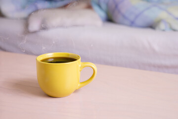 A cup of morning coffee standing close to the bed