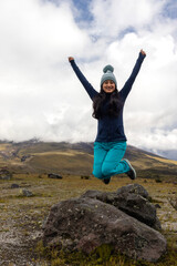 Young woman jumping with her arms raised after a mountain hike, concept of freedom, lifestyle, and travel